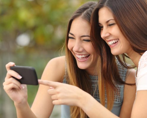 mobile game promotion: two women having fun playing a game on their smartphone