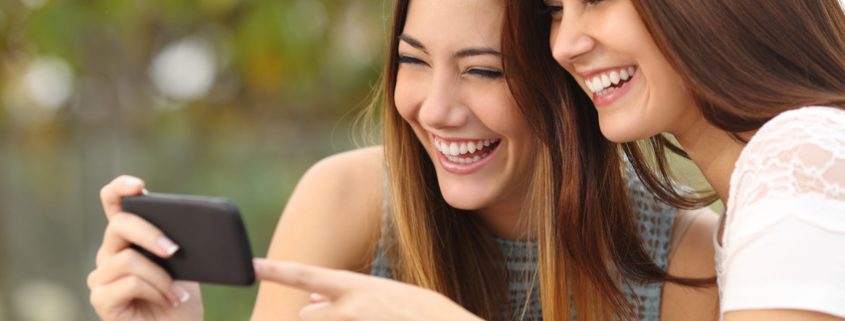 mobile game promotion: two women having fun playing a game on their smartphone